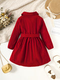 Red dress with a belt on a textured surface with decorative items.