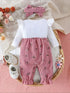 Baby outfit with pink floral romper and white top on a textured surface with flowers and shoes.