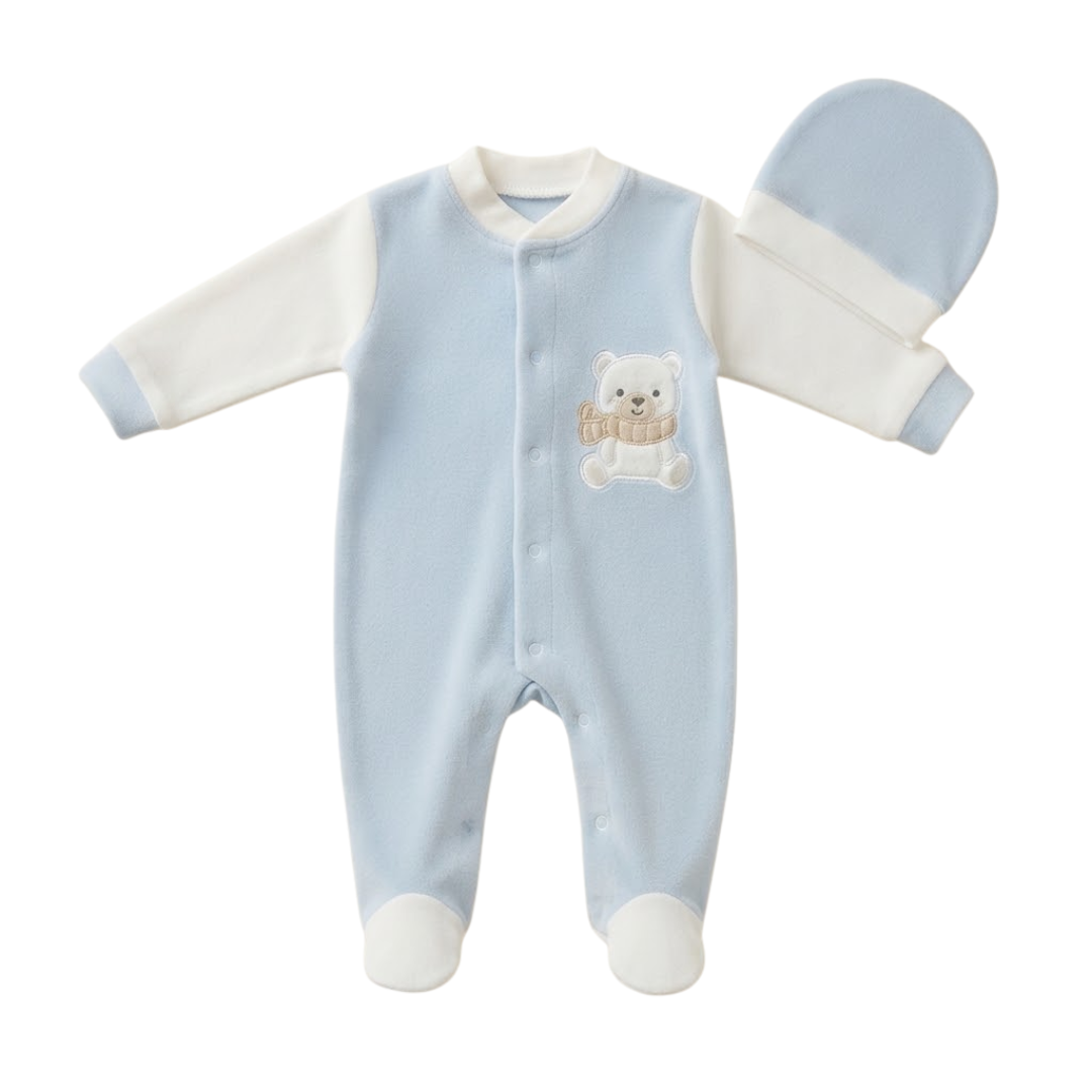 A baby footed sleeper set in light blue and white, featuring a long-sleeve one-piece with a small teddy bear applique on the chest, shown alongside a matching blue and white bonnet on a white background.