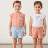 Two young girls wearing mismatching outfits with floral patterns on a plain background