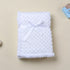 Folded white textured blanket with a bow on a beige background