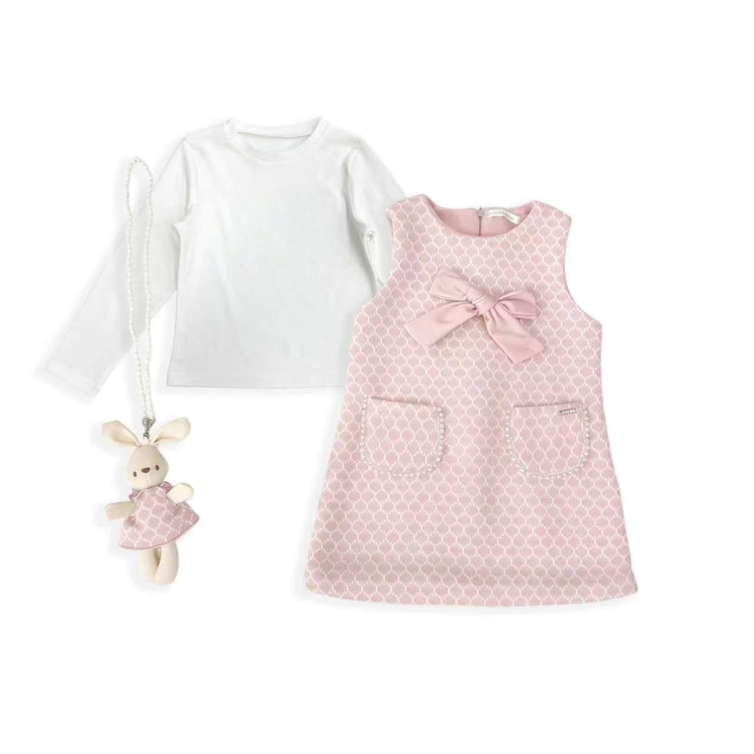 A baby girl's three-piece outfit set featuring a white long-sleeve shirt, a pink patterned sleeveless dress with a bow and pockets, and a matching pink plush bunny keychain.