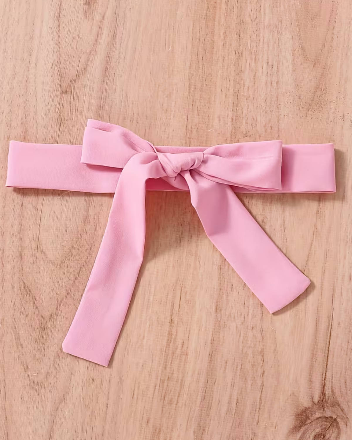 Pink belt with a bow on a wooden surface