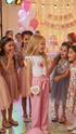 Group of young girls at a birthday party with balloons and a cake.
