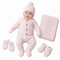 A baby wearing a light pink cable-knit one-piece outfit with a matching knit hat, mittens, booties, and a folded blanket on a plain white background.