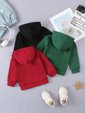 Three hoodies in black, red, and green on a gray surface with shoes and a hat.