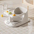 White baby bath seat with toys on a tiled bathroom floor