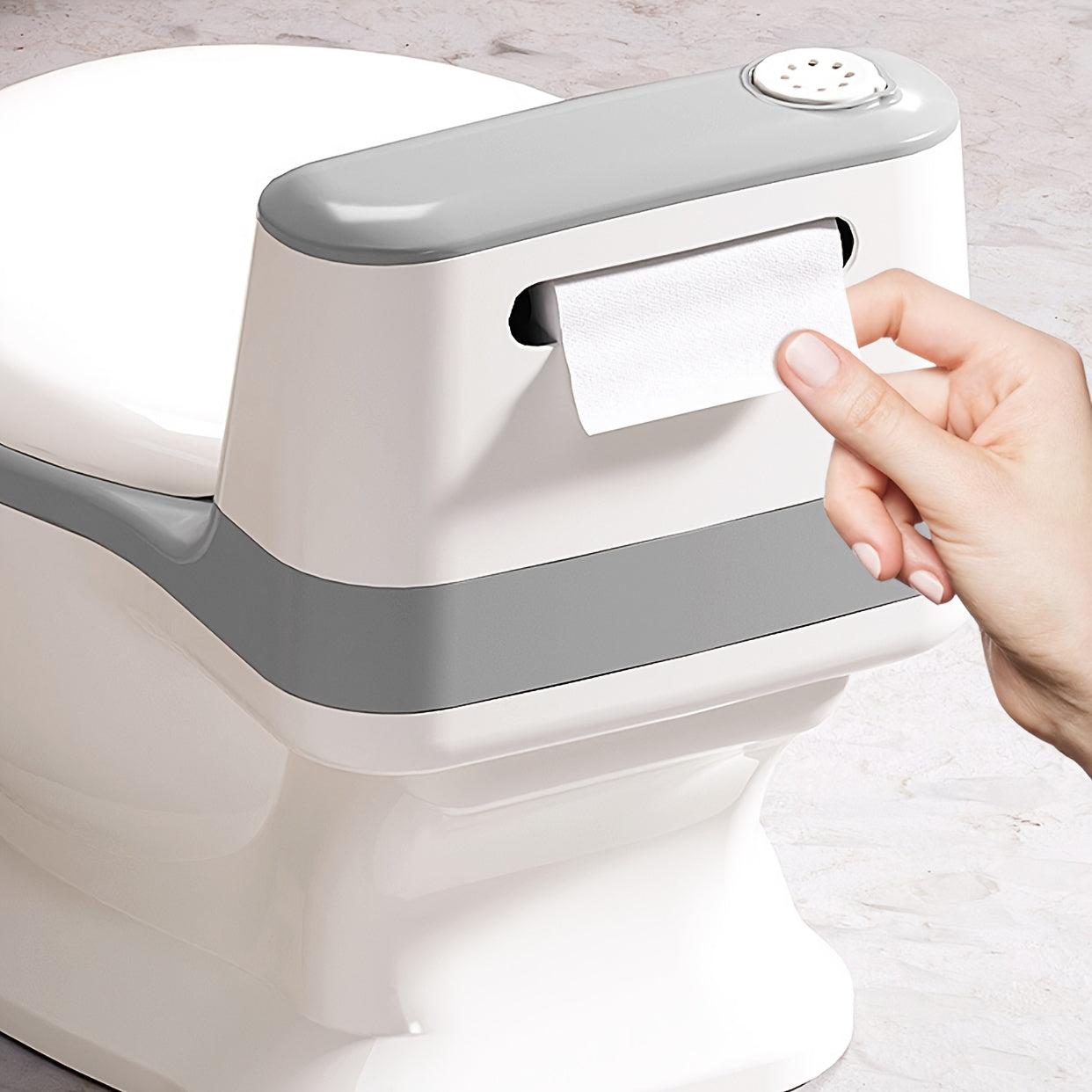 Hand using a white and gray paper towel dispenser on a light wooden surface