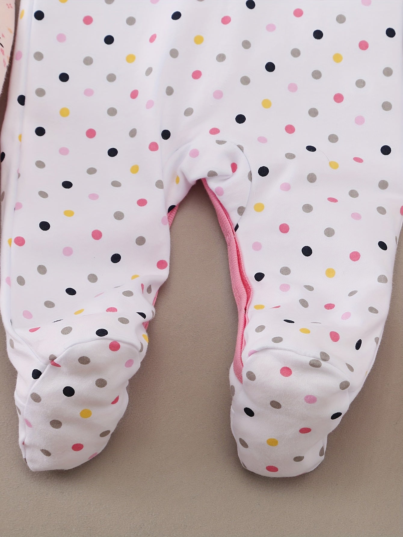 Baby onesie with polka dot pattern on a beige background
