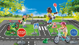 Playmobil toy set with children on bicycles at a crossroads with traffic signs and road markings.