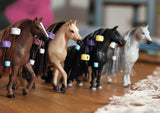 Model horses with colorful halters on a wooden floor