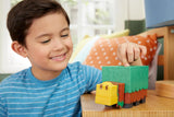 Child playing with a toy train made of interlocking blocks on a wooden table.