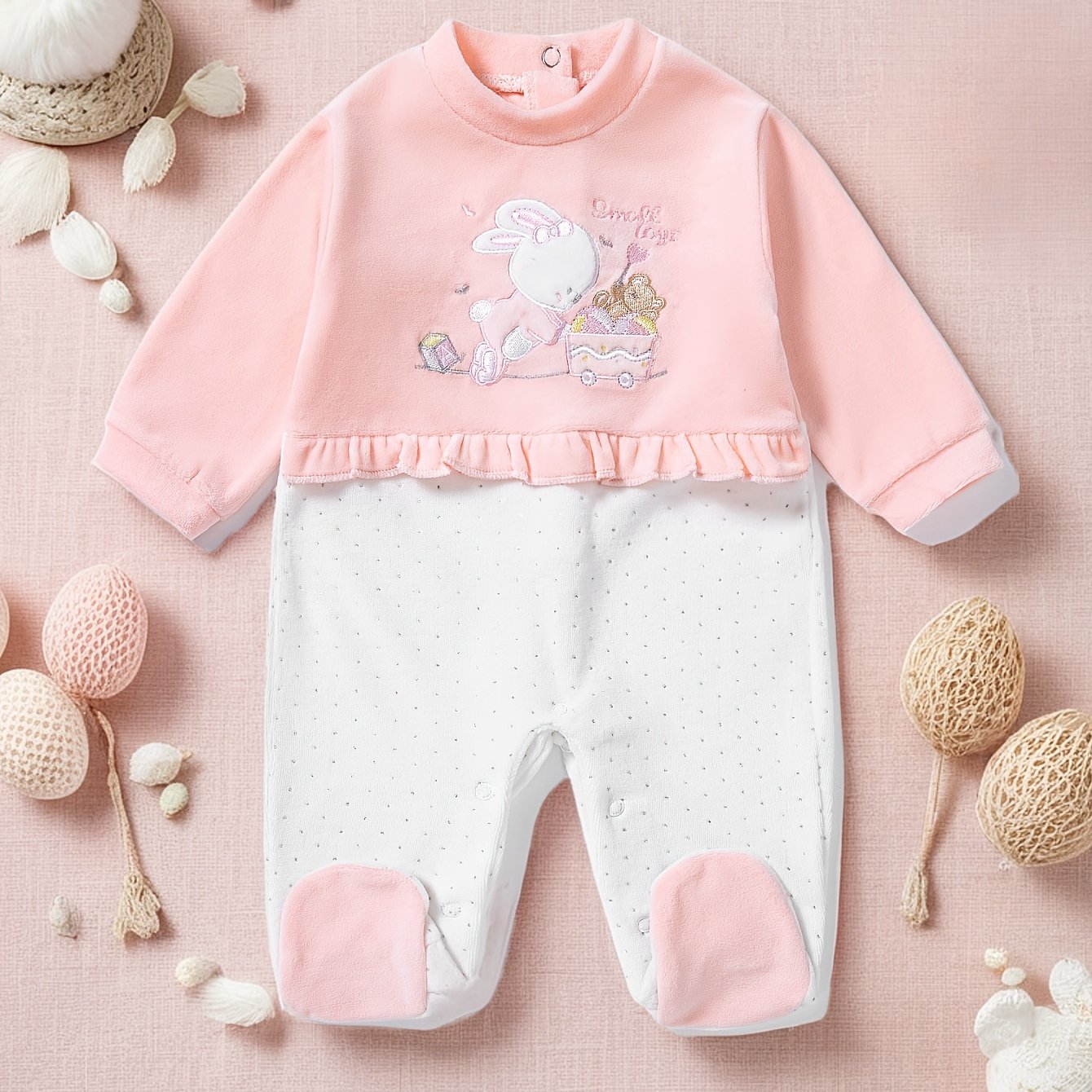 Baby outfit with pink top and white pants on a soft pink background
