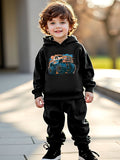 Child wearing a black hoodie with a monster truck design outdoors