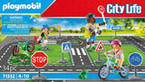 Playmobil City Life toy set with children on bicycles and traffic signs on a road layout.