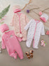 Collection of baby outfits and accessories on a textured surface with decorative elements.