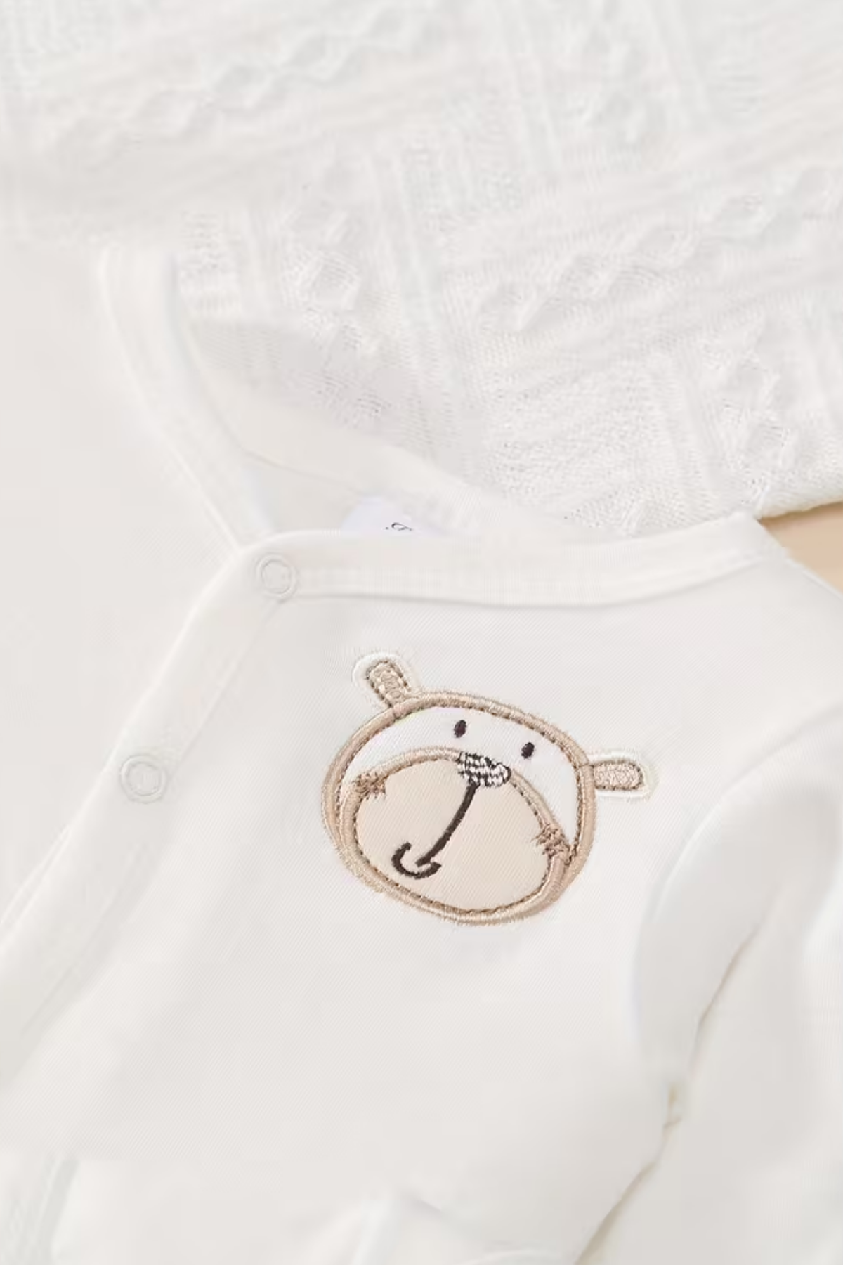 White baby outfit with a bear face design on a white background