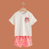 Children's outfit with white t-shirt and pink shorts featuring a cartoon character on a brown background
