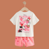 Children's outfit with a white t-shirt and pink shorts featuring Disney characters on a brown background.