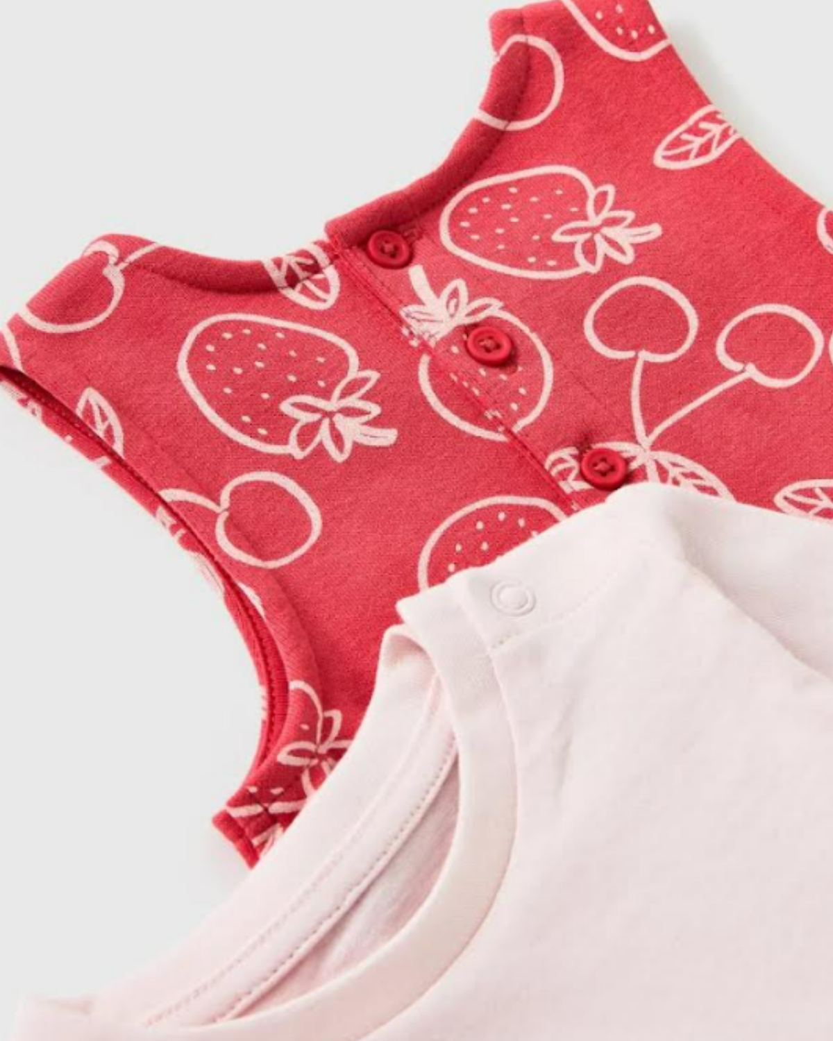 Red baby romper with strawberry pattern on a light gray background