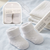 White baby socks with packaging on a striped background