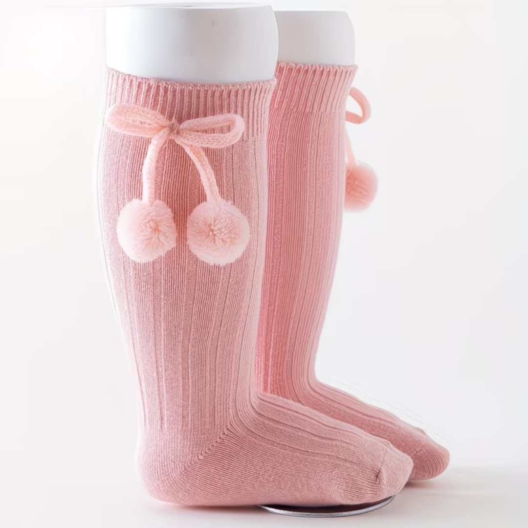 Pink knee-high socks with a bow and pom-poms on a white background