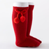 Red knee-high socks with pom-poms and a bow on a white background