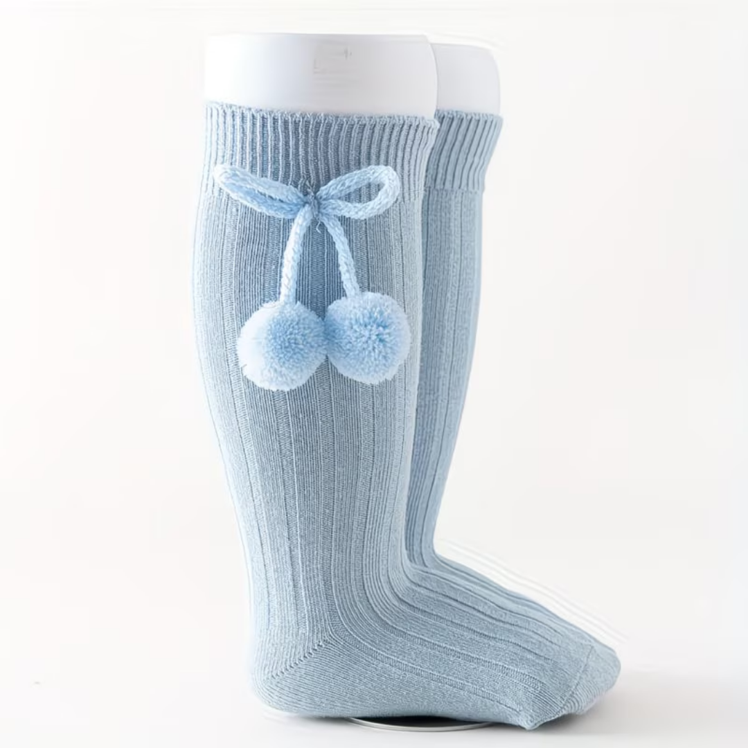 Light blue knee-high sock with pom-poms and a bow on a white background