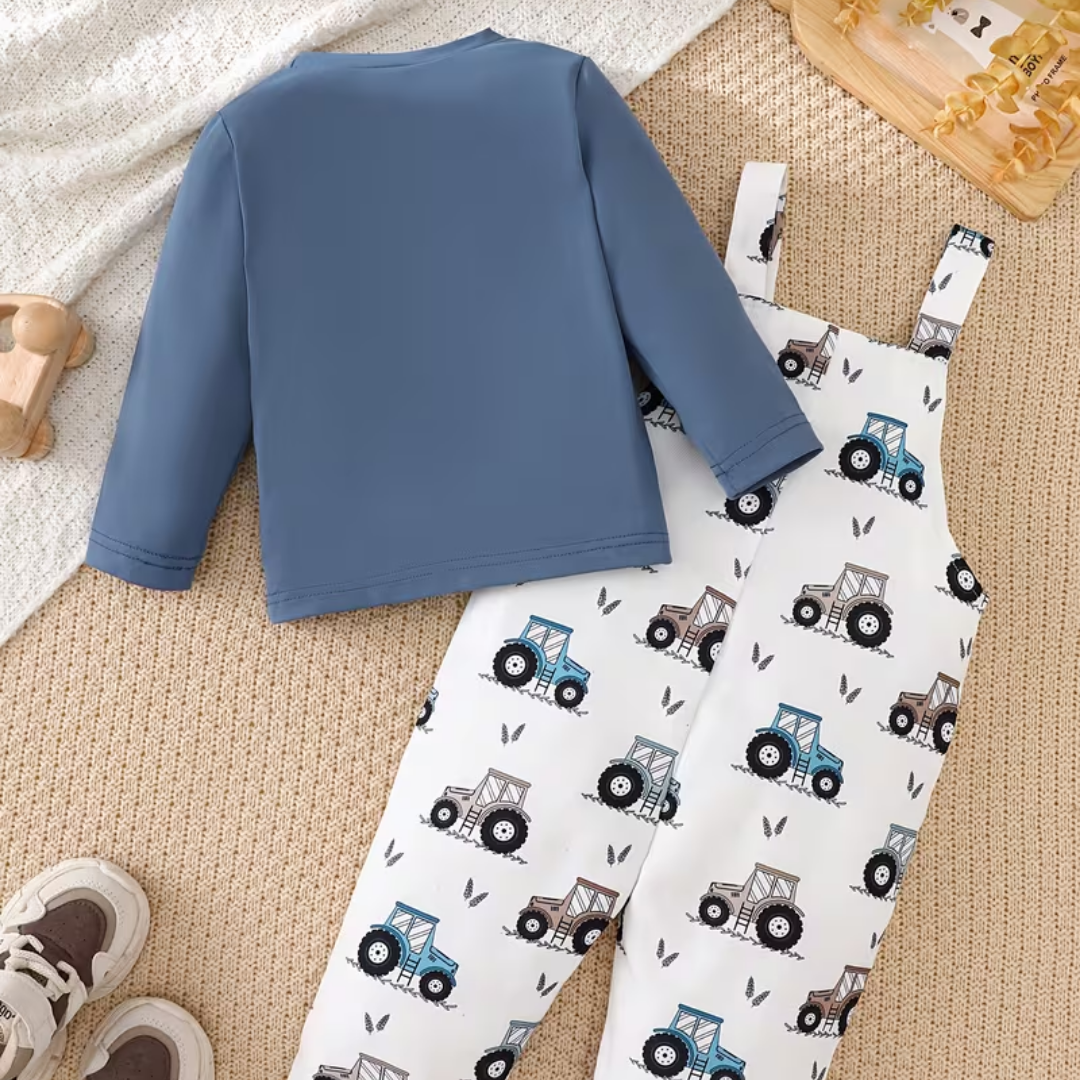 Children's blue long-sleeve shirt and white pants with tractor pattern on a beige carpet.