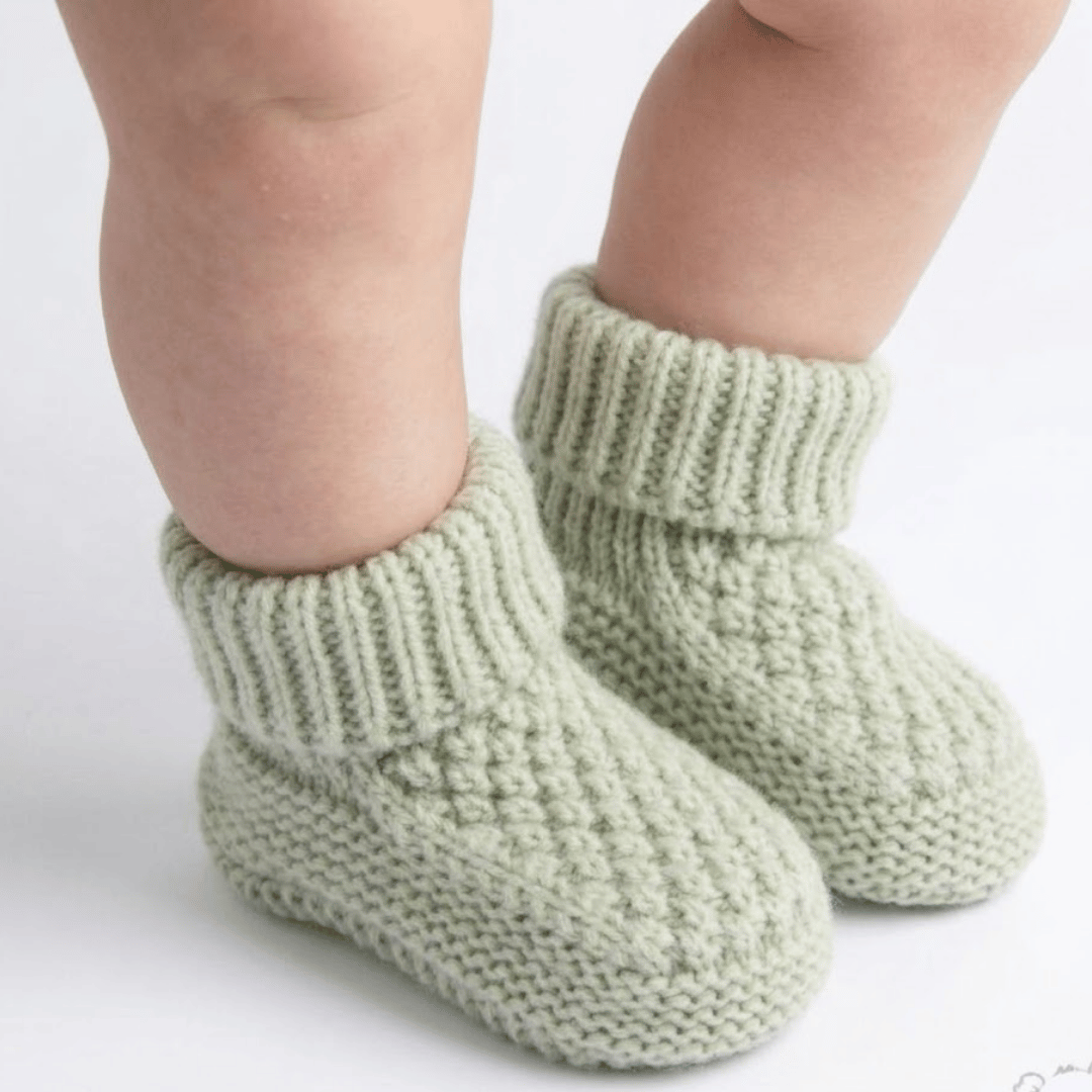 Green knitted baby socks on a white background