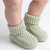 Green knitted baby socks on a white background
