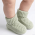 Green knitted baby socks on a white background