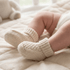 Baby's feet wearing beige knitted socks on a soft surface