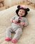 A baby lying on a cream carpet wearing a gray Minnie Mouse onesie with a black and pink Minnie Mouse hat.