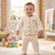 Smiling baby dressed in a cozy cream fleece two-piece outfit in a nursery.