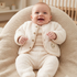 Smiling baby sitting in a lounger wearing a 3-piece cream fleece jacket set