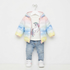 A toddler girl's winter outfit set hanging on a white hanger against a plain white background. The set includes a pastel rainbow gradient puffer jacket with a unicorn graphic on the front, light-wash blue jeans, and white sneakers.