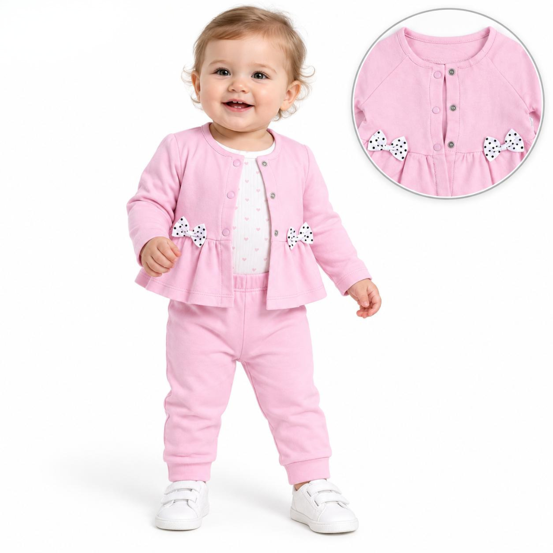 A toddler wearing a pink two-piece outfit consisting of a cardigan and matching pants, with white shoes. The image includes a circular inset showing a close-up of the cardigan's buttoned neckline and bow details.