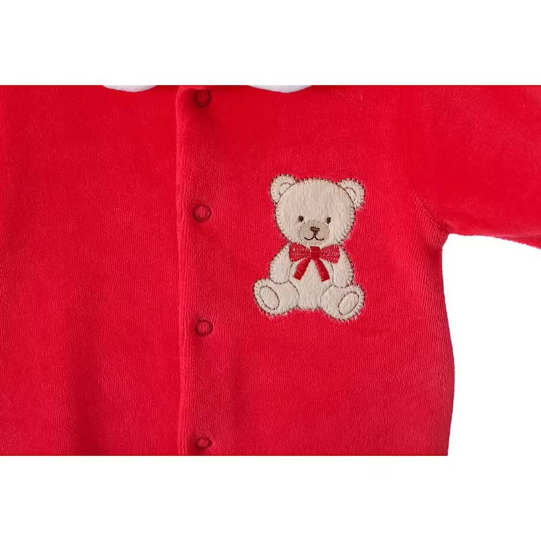 Embroidered teddy bear detail on red velour fabric.