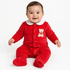 Baby sitting in a red velour footed sleeper with a white collar and teddy bear embroidery.