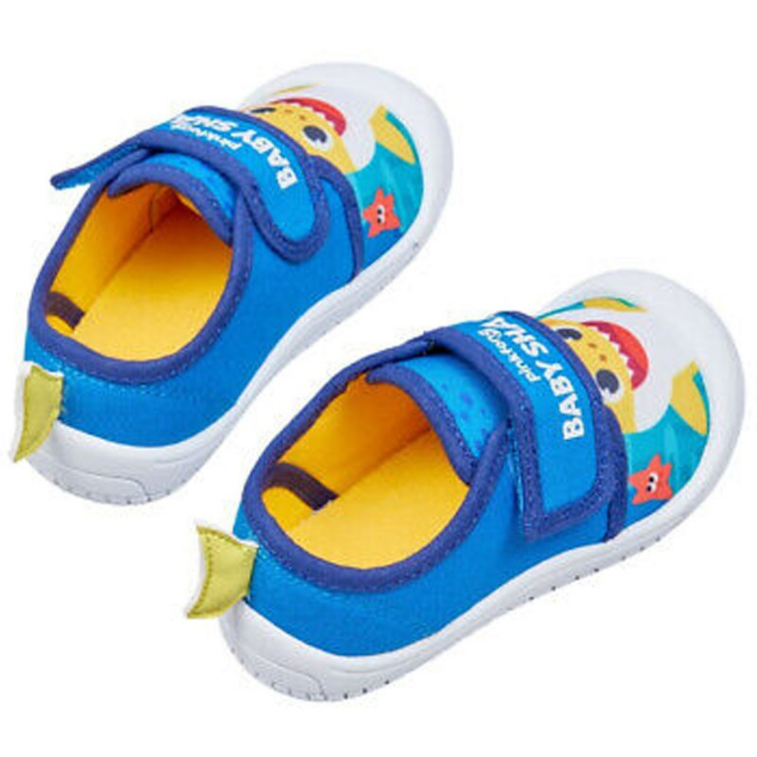 A pair of children's slip-on shoes with blue uppers, yellow interiors, white soles, and cartoon shark graphics on a white background.