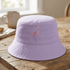 Purple bucket hat with flamingo design on a wooden table