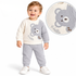 A baby boy wearing a two-piece waffle-knit sweater and pants set in cream and light gray, featuring a bear face graphic and 'Hello' text. An inset circle shows a close-up of the bear graphic and knit texture.