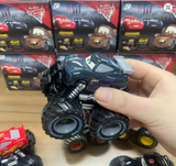 Toy monster truck held by a hand with toy car boxes in the background