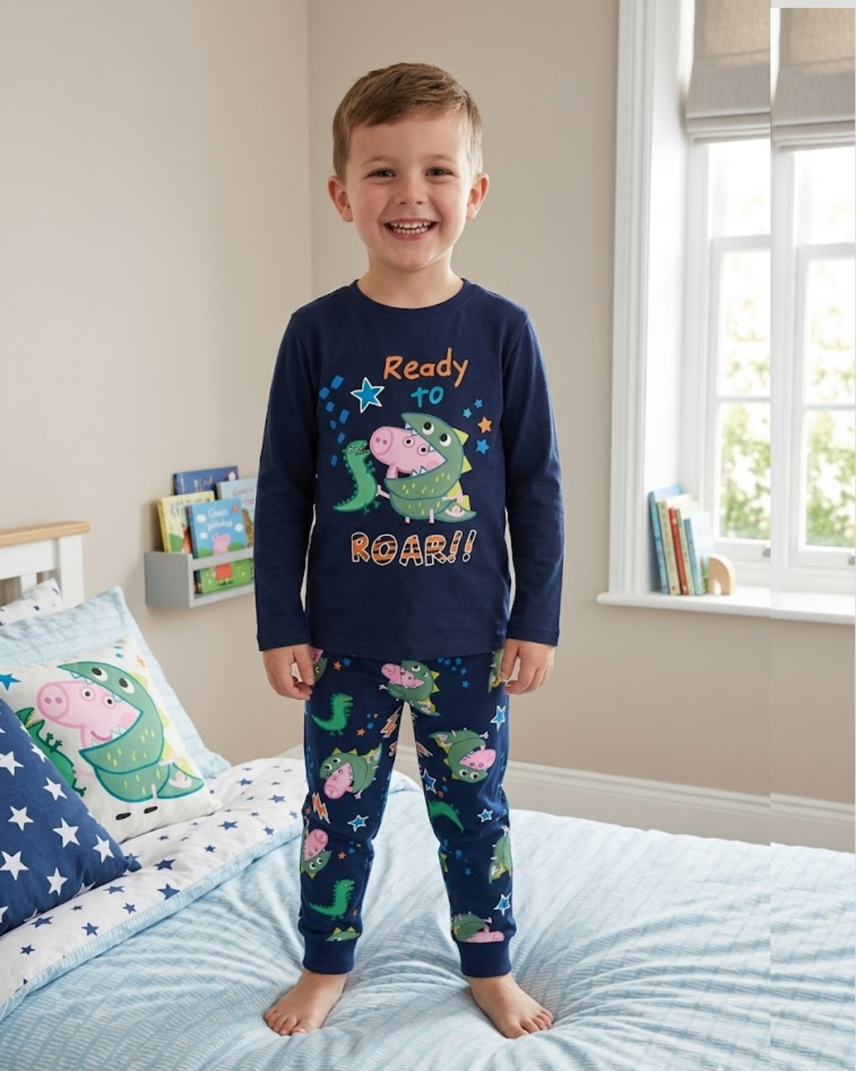 A boy wearing the Peppa Pig themed pyjama set standing on the bed.