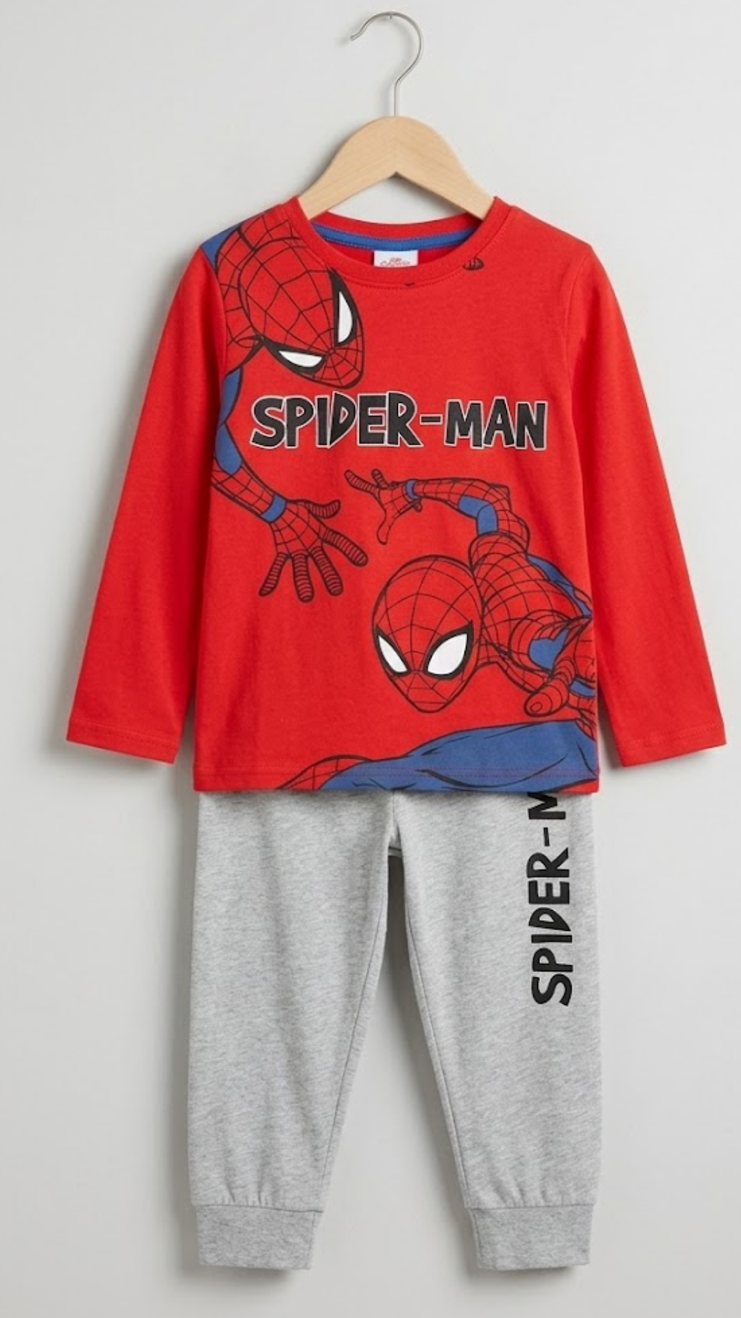 Spider-Man children's outfit with red shirt and gray pants on a hanger against a light gray background