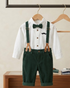 Children's outfit with white shirt, green suspenders, and dark green pants on a wooden hanger.