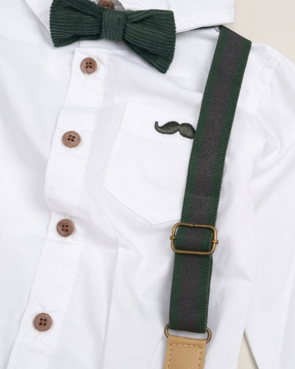 Green bow tie and suspenders on a white shirt with brown buttons.