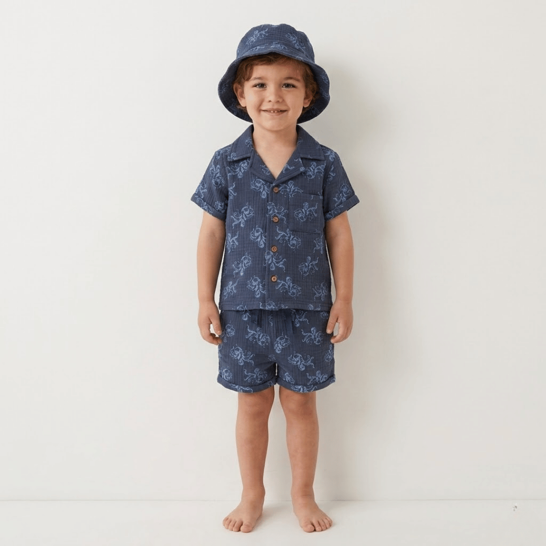 Child wearing a navy patterned outfit with a matching hat on a white background