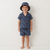 Child wearing a navy patterned outfit with a matching hat on a white background